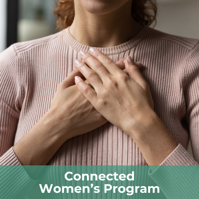 A woman tenderly holds her hands over her heart as if in self acknowledgement or reflection. There is a text bar on the bottom of the image that reads Connected Women's Program.